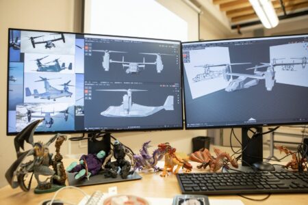 On three computer monitors, there are different views of a helicopter that a NBCCD 3D Digital Design student has modelled.