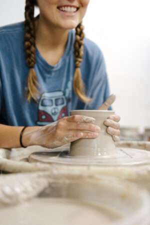Student shaping clay on a pottery wheel in the ceramics studio.