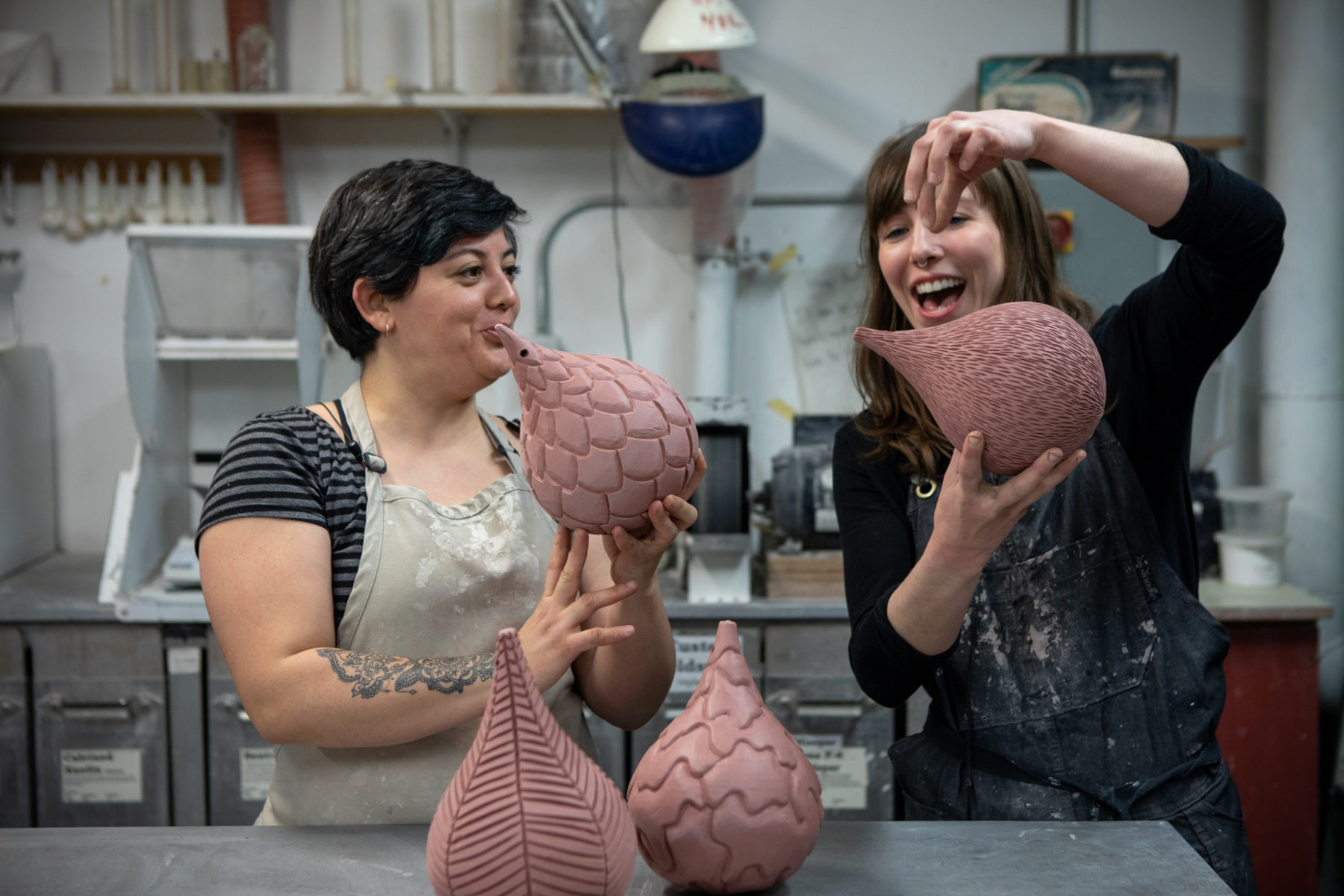 Two students bonding over their bud-like sculptures in a ceramics class.