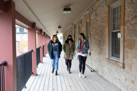 Three students walking down an exterior corridor.