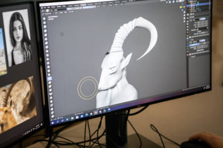 A 3d-modelled creature with a long antler is the main focus on the computer screen. An NBCCD 3D Digital Design student made it.