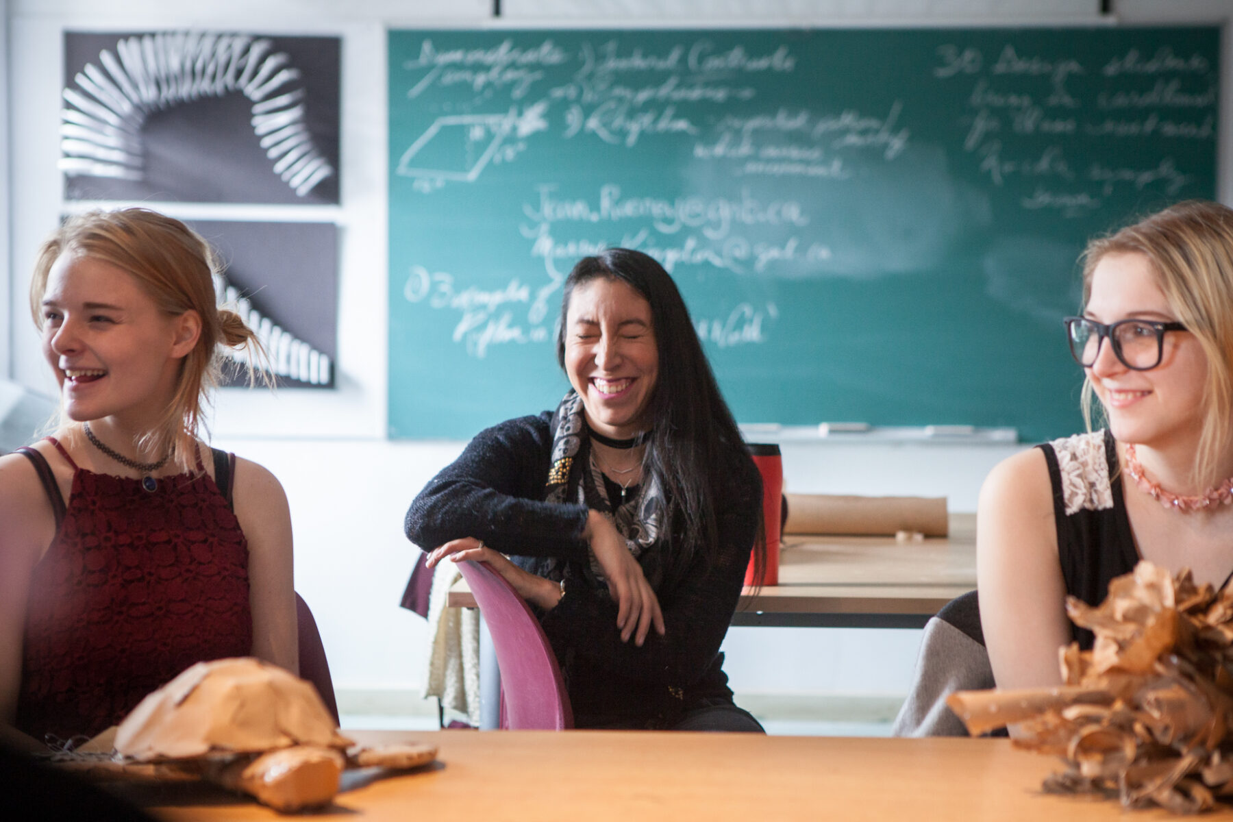 Three women classmates laugh in a Foundation Visual Arts classroom.