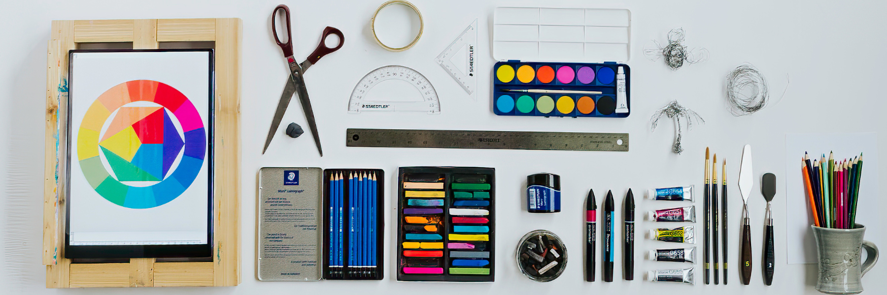 A variety of craft and design tools used by students at the NBCCD programs displayed on a white floor.