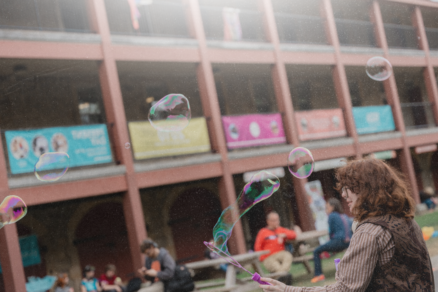 Craft and design student blowing bubbles outside of campus building on orientation day.